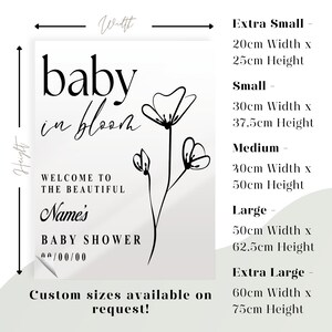 May include: A black and white printable baby shower sign featuring a floral design. The text reads "baby in bloom" and "Welcome to the beautiful Name's Baby Shower 00/00/00". The sign also includes a size chart with dimensions in centimetres.