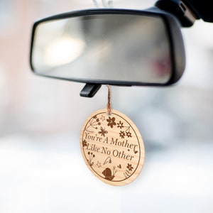 May include: A round wooden car air freshener with the text "You're A Mother Like No Other" surrounded by a floral design.