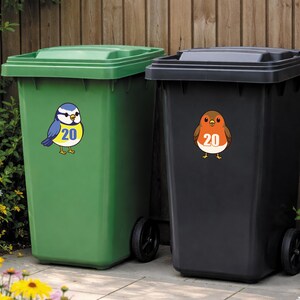 Op de afbeelding: Twee vuilnisbakken, een groene en een zwarte, met vogelstickers. De groene bak heeft een blauw-gele vogelsticker met het nummer 20. De zwarte bak heeft een bruin-oranje vogelsticker met het nummer 20.