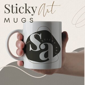 May include: White ceramic mug with a black and white logo that says "Sticky Art" in a stylized font. The logo is inside a brown outline of a rounded shape.