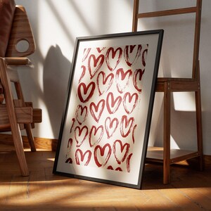 May include: A framed print with a white background and a pattern of red brushstroke hearts.