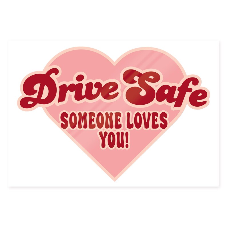 May include: A pink heart-shaped sticker with the words "Drive Safe" in red, retro-style lettering. Below, the text "SOMEONE LOVES YOU!" is also in red. The sticker is designed to be placed on a car or other vehicle.
