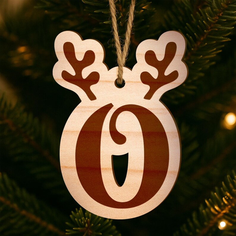 May include: Wooden Christmas ornament shaped like a reindeer head with the number "0" in the center. The ornament is made of light-colored wood with a brown number and antlers. A twine loop is attached for hanging on a Christmas tree.