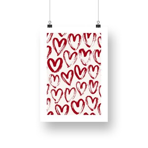 May include: A white framed print with a red and white pattern of hand-drawn hearts.