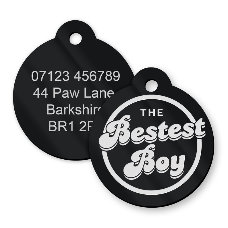 Puede incluir: Dos placas negras para mascotas. Una placa presenta el texto "THE Bestest Boy" en blanco, con una fuente retro, dentro de un c&iacute;rculo blanco. La otra placa tiene un n&uacute;mero de tel&eacute;fono y una direcci&oacute;n en texto blanco.