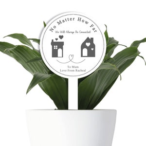 May include: White round plant stake with the text "No Matter How Far We Will Always Be Connected" and two house illustrations with hearts. The text "To Mum Love From Racheal" is also included.