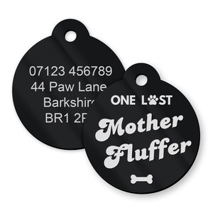 Op de afbeelding: Twee zwarte ronde huisdier-ID-tags. De grotere tag heeft de tekst "ONE LOST" en "Mother Fluffer" in wit met een pootprint en een beensymbool. De kleinere tag heeft de tekst "07123 456789", "44 Paw Lane", "Barkshire" en "BR1 2F" in wit.