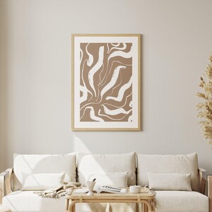 May include: A framed abstract print with a brown background and white abstract shapes. The print is in a wooden frame.