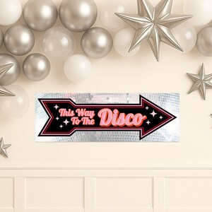 Pu&ograve; includere: Un cartello nero a forma di freccia con le parole "This Way To The Disco" in rosa e bianco. La freccia ha un bordo rosso e uno sfondo a palla da discoteca argentata. Decorazioni con stelle e palloncini argentati sullo sfondo.