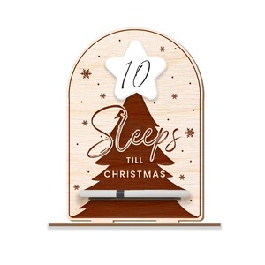 Puede incluir: Un letrero de cuenta atr&aacute;s de Navidad de madera con un dise&ntilde;o de &aacute;rbol marr&oacute;n y el texto "Sleeps till Christmas". Una estrella blanca con el n&uacute;mero 10 est&aacute; en la parte superior del &aacute;rbol. Se incluye un marcador blanco.