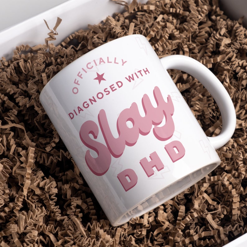May include: White ceramic mug with a pink graphic that says "Officially Diagnosed With Slay DHD".