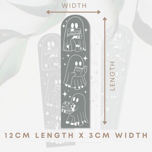 May include: A grey bookmark with a repeating pattern of white ghosts holding books. The bookmark is 12 cm long and 3 cm wide.  "12CM LENGTH X 3CM WIDTH" is printed at the bottom of the bookmark.