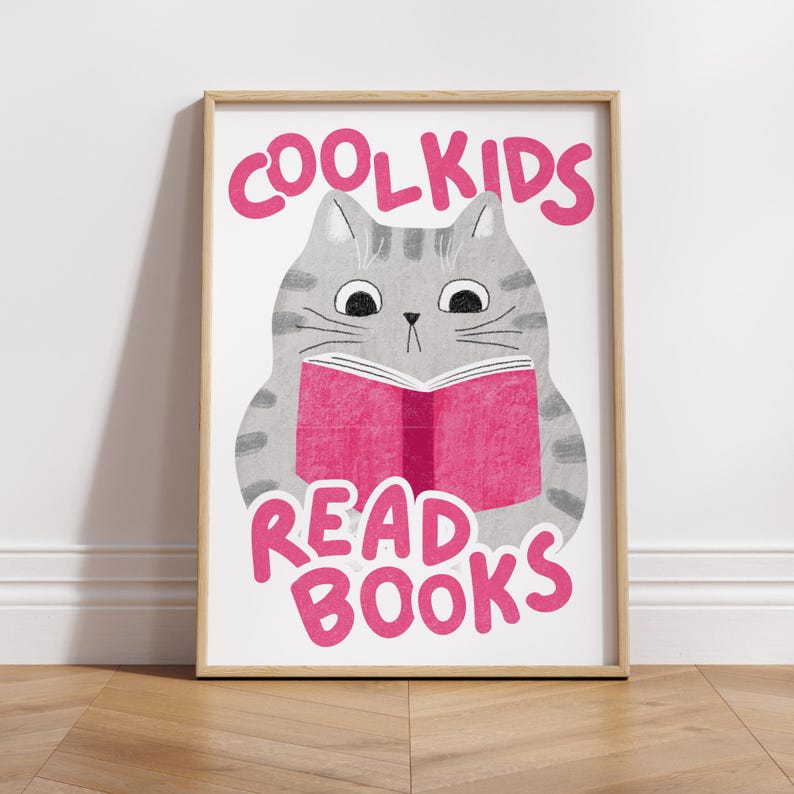 May include: A framed print with a gray cat reading a pink book. The text on the print reads "Cool Kids Read Books".