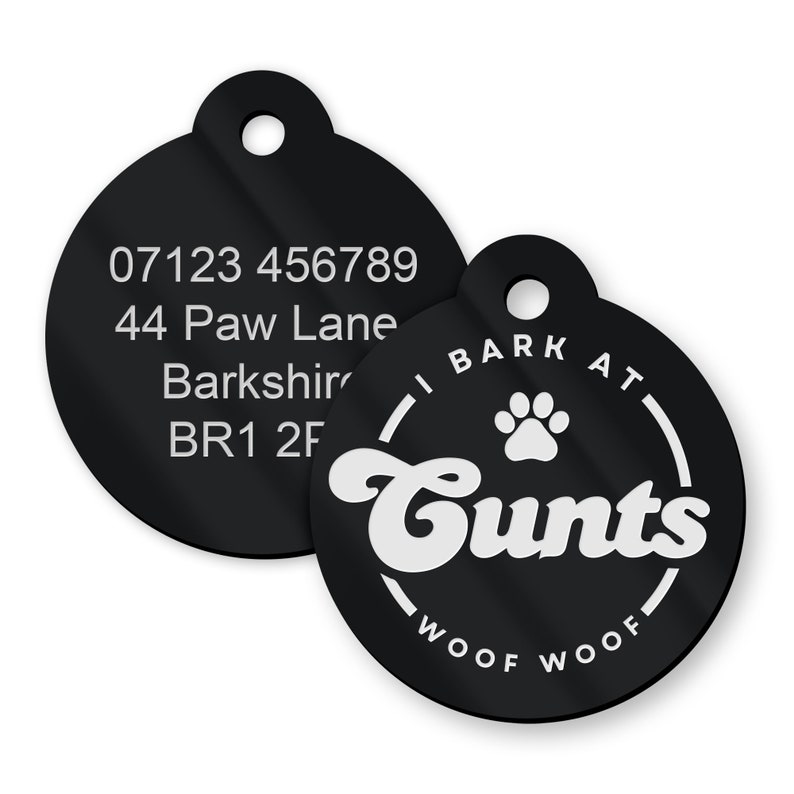 Op de afbeelding: Twee ronde zwarte hondenpenningen met witte tekst. De eerste penning heeft een telefoonnummer, een adres en een postcode. De tweede penning heeft de tekst "I bark at Cunts" in een cirkel met de woorden "woof woof" eronder.