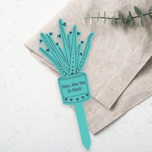 Op de afbeelding: Een turquoise blauwe plantensteun met een uitsnijding van een alo&euml;plant en de tekst "Mum, Aloe You So Much!" De steun is omringd door kleine hartjes.