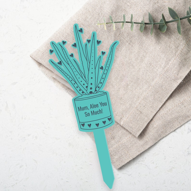 Op de afbeelding: Een turquoise blauwe plantensteun met een uitsnijding van een alo&euml;plant en de tekst "Mum, Aloe You So Much!" De steun is omringd door kleine hartjes.