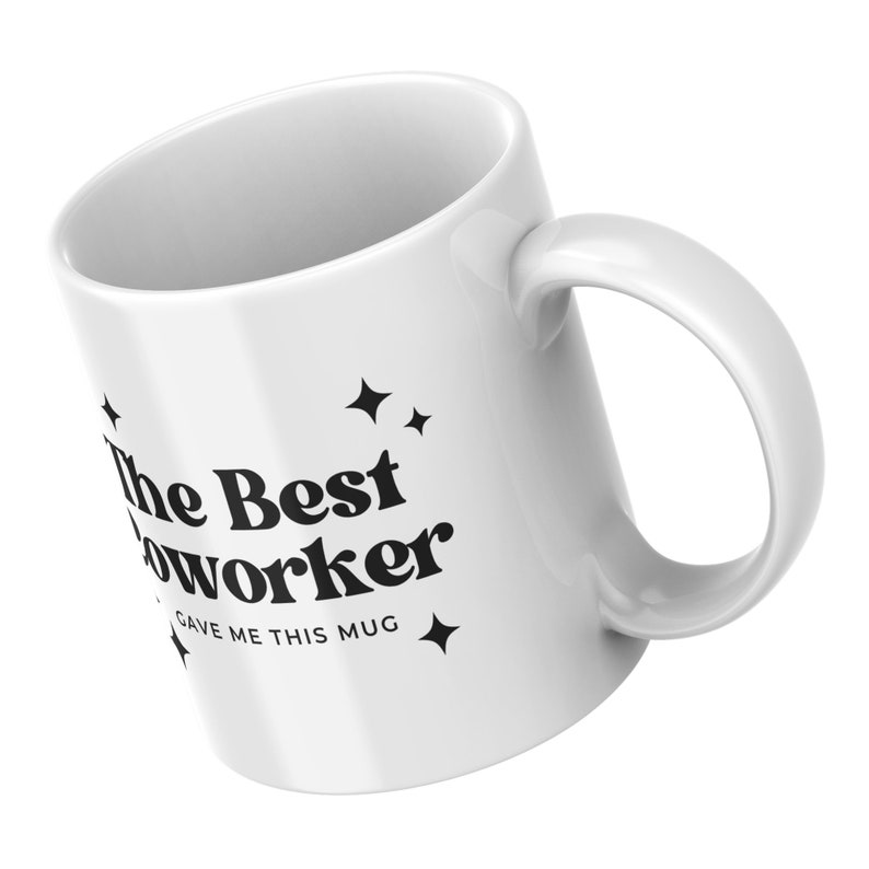Op de afbeelding: Witte keramische mok met zwarte tekst die "The Best Coworker Gave Me This Mug" luidt met kleine sterren aan weerszijden van de tekst.