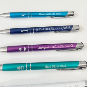 May include: Four different colored pens with silver accents and engraved text. The pens are blue, navy blue, purple, and teal. The text on the pens reads "Dance with the music", "If Dad can't fix it - it's fucked", "Strongest Dad In The World", and "Best Plant Dad".