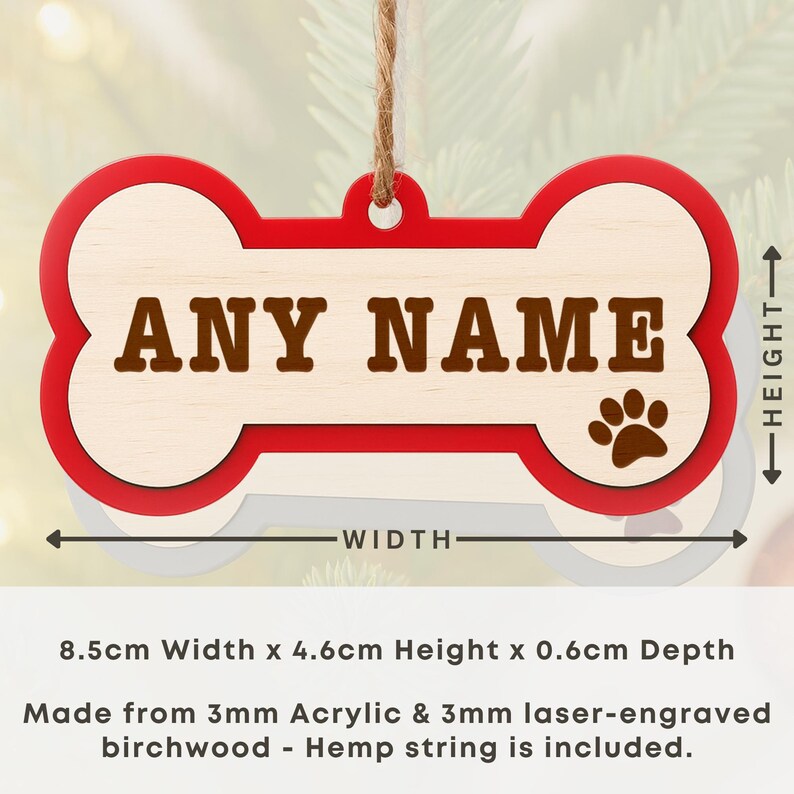 Peut inclure: Ornement en forme d'os de chien avec une bordure rouge et un centre en bois clair. Le texte "ANY NAME" est affich&eacute; en lettres marron. Une empreinte de patte est sur le c&ocirc;t&eacute; droit. L'ornement mesure 8,5 cm de large et 4,6 cm de haut.