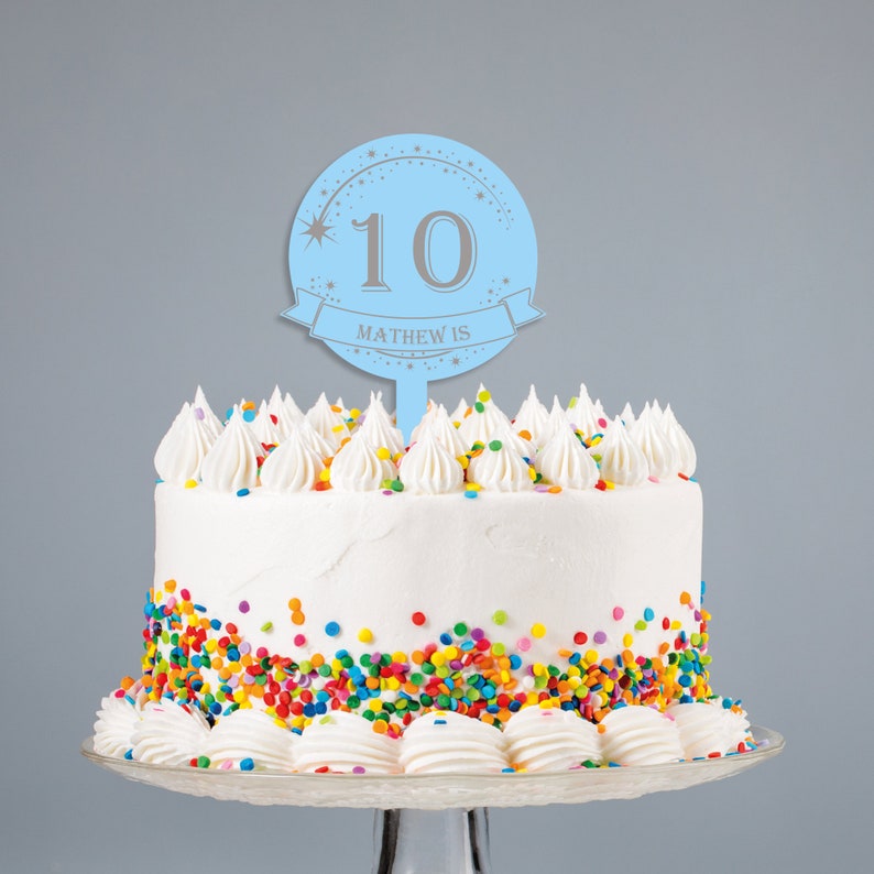 May include: Blue and silver cake topper with the number 10 and the text "Matthew is" on a white cake with colorful sprinkles.