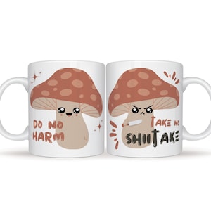 May include: Two white mugs with a mushroom design. One mug says "Do No Harm" and the other says "Take No Shiitake".
