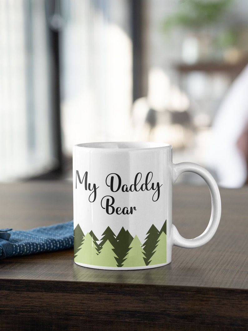 May include: White ceramic mug with a black and green design. The mug has the text "My Daddy Bear" printed on it.