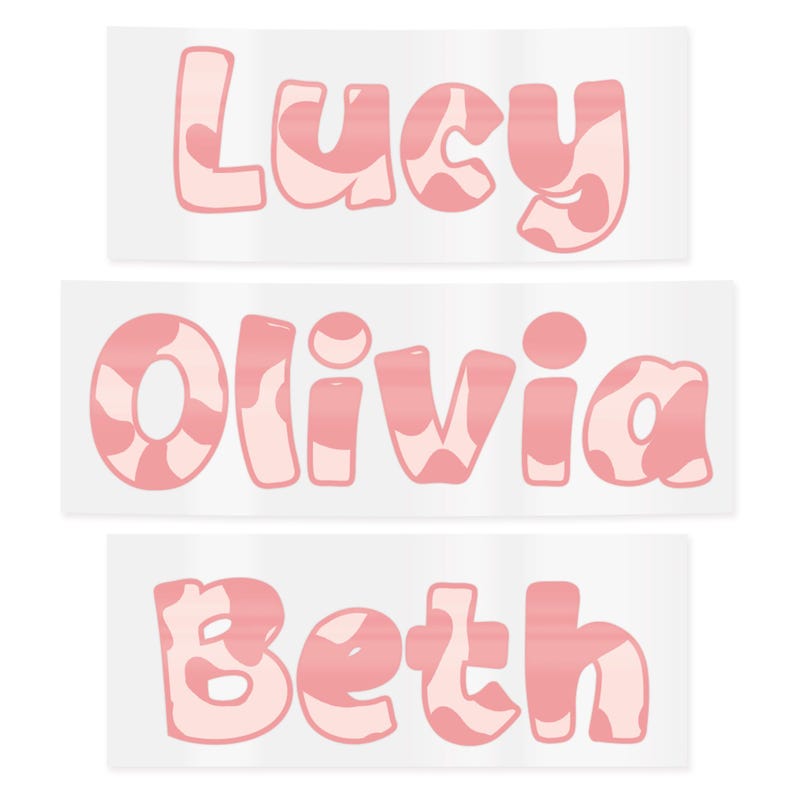 May include: Three stickers with the names "Lucy", "Olivia", and "Beth". Each name is in a bubble letter font with a pink and white cow print design. The stickers are rectangular with a white background.