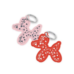 May include: Two keychains shaped like balloon dogs, one pink and one red. Each keychain is decorated with heart patterns and has a silver key ring attached. The keychains are on a white background.
