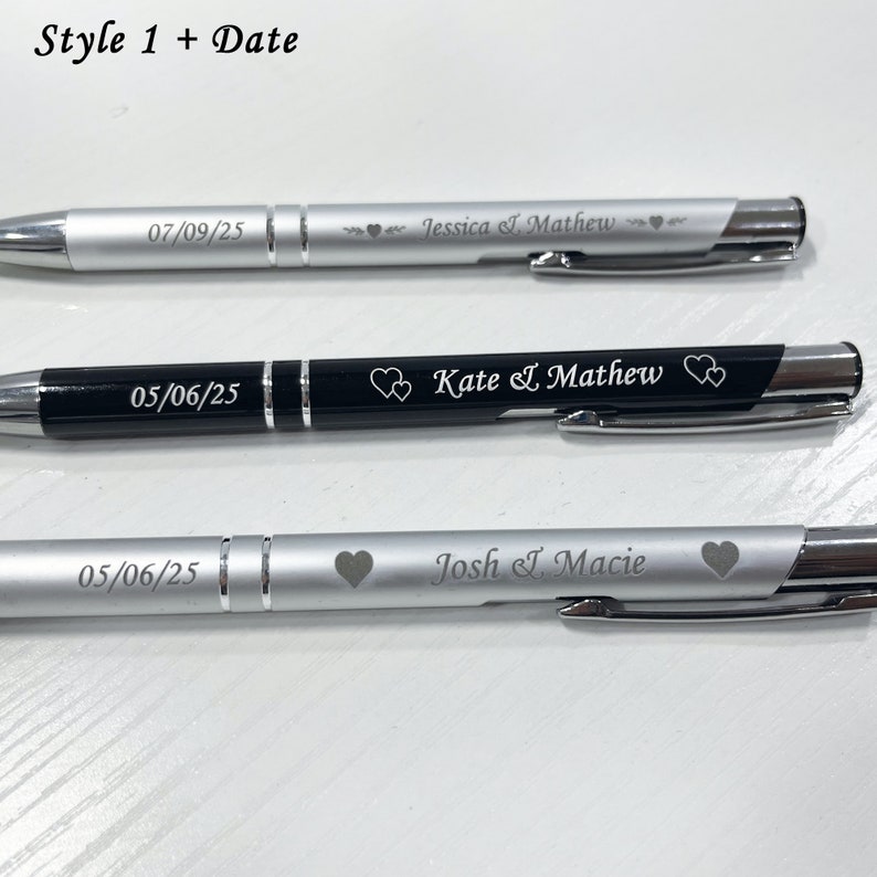 May include: Three silver and black pens with engraved dates and names. The pens have a silver clip and a black barrel. The names are Jessica I. Mathew, Kate & Mathew, and Josh I. Macie.
