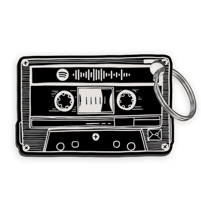 Pu&ograve; includere: Illustrazione in bianco e nero di un nastro cassette con un portachiavi. Il nastro ha un'etichetta bianca con un logo Spotify stilizzato e il testo "Spotify" su di essa.