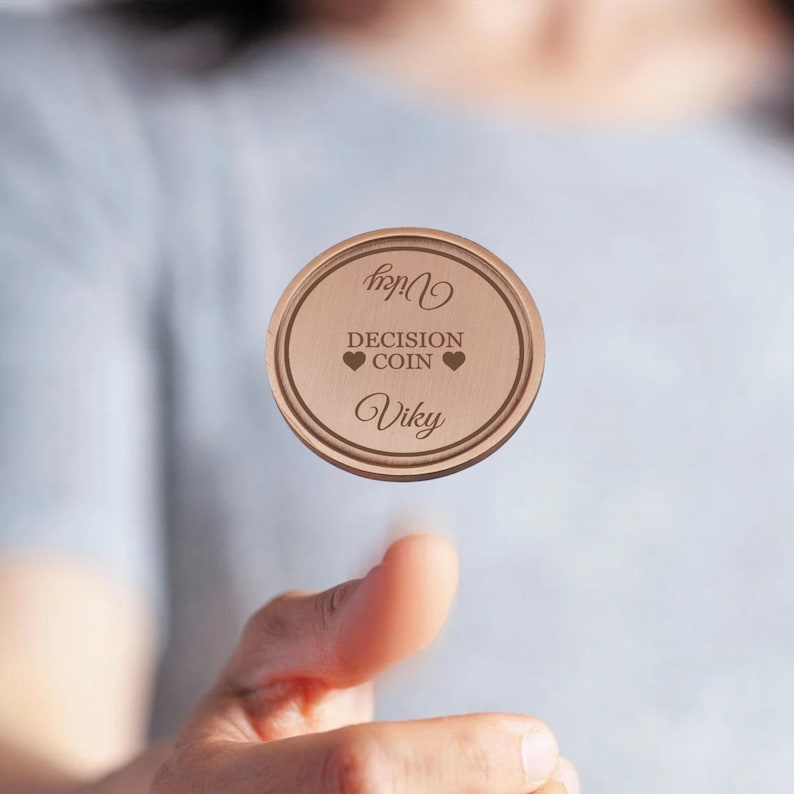 May include: A wooden decision coin with the words "Decision Coin" and two hearts engraved on it. The coin also has the name "Vicky" engraved on it.
