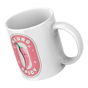 Puede incluir: Taza de cer&aacute;mica blanca con una pegatina rosa y blanca que presenta un chile rojo con una cara sonriente y el texto "Neuro Spicy".