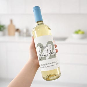 May include: A clear wine bottle with a light blue cap and a white label. The label reads "Happy Birthday" with the number "22" in a large font. The text "Happy birthday Jessica! Lots of love, from Mum & Dad" is also on the label.
