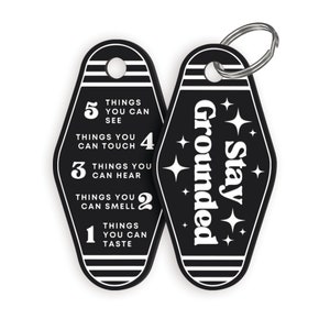 May include: Black and white keychain with a motel key design. One side says "Stay Grounded" with stars. The other side has a list of five things you can do with your senses: see, touch, hear, smell, and taste.