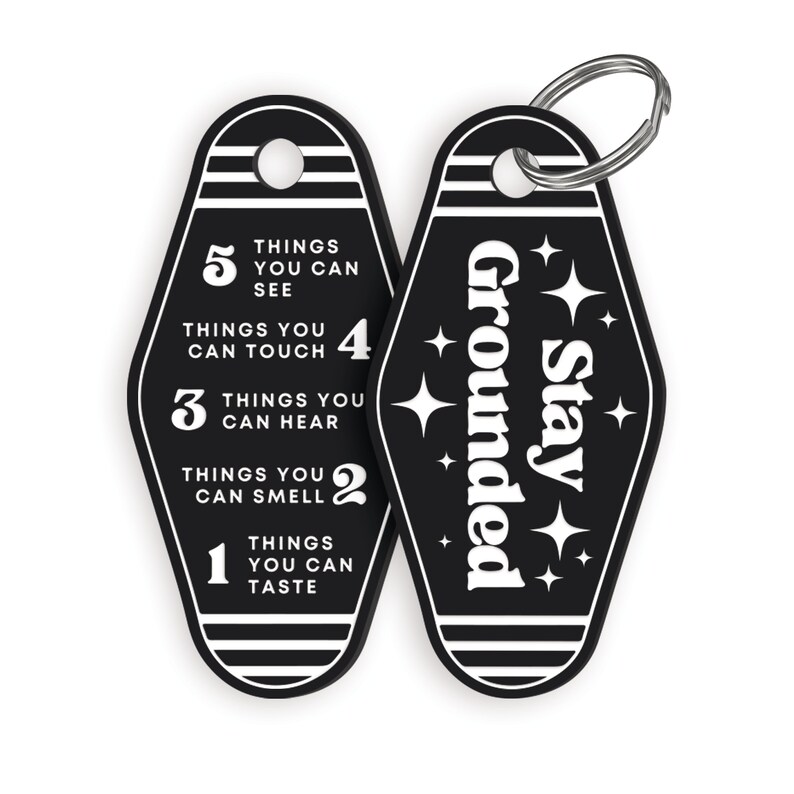 May include: Black and white keychain with a motel key design. One side says "Stay Grounded" with stars. The other side has a list of five things you can do with your senses: see, touch, hear, smell, and taste.