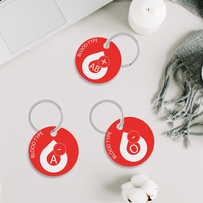 May include: Three red keychains with silver rings. Each keychain has a white blood drop with a letter and a plus or minus sign. The keychains read "BLOOD TYPE" and "AB+", "A-", and "O-".