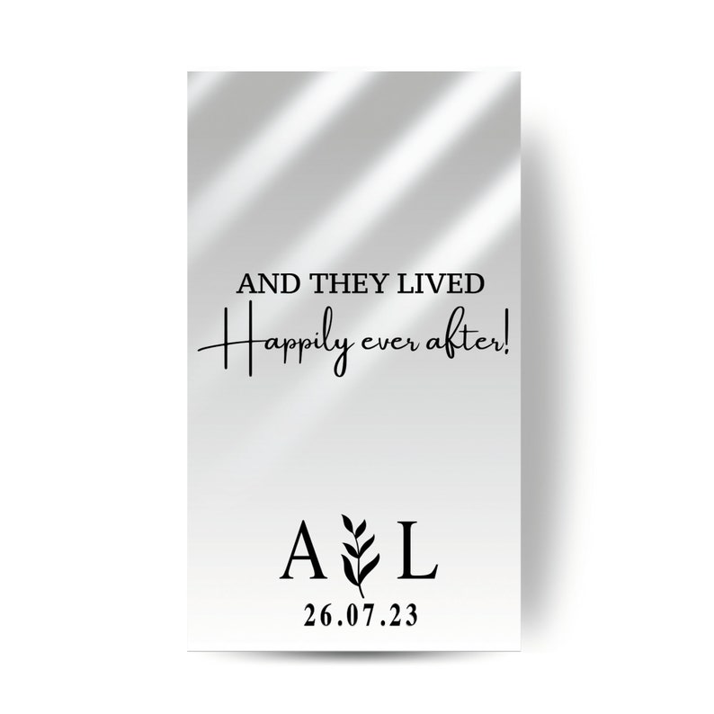 以下が含まれることがあります： 影の効果のある白い背景。テキスト「AND THEY LIVED happily ever after!」は黒色です。テキストの下には、植物の小さなグラフィックが間に挟まれた「A」と「L」の文字があります。日付「26.07.23」は文字の下にあります。