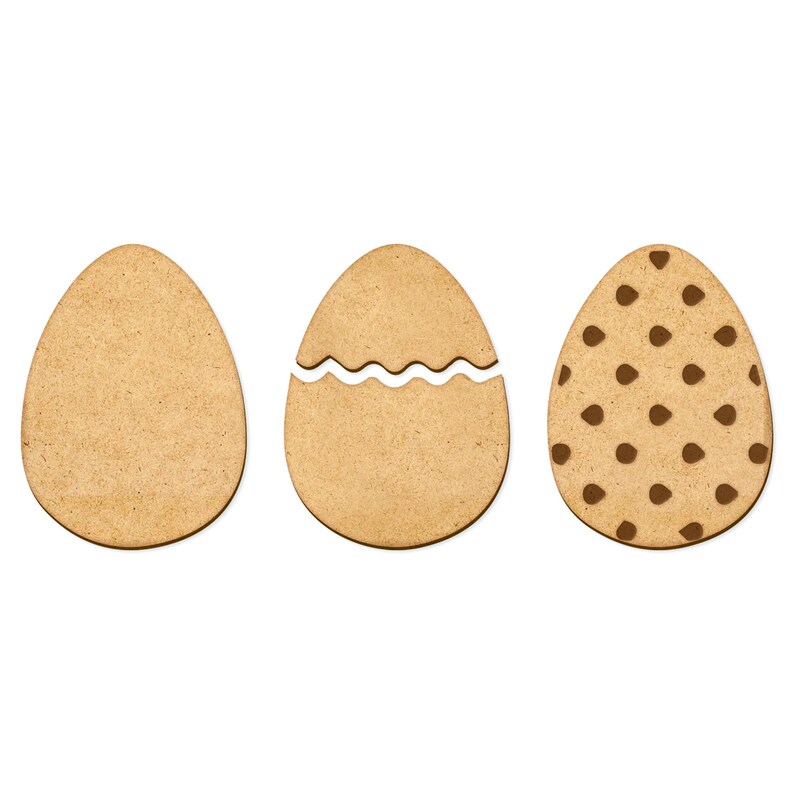 May include: Three wooden Easter egg shapes. One is plain, one has a wavy line cut out, and one has a brown polka dot pattern.