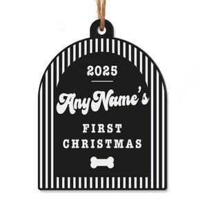 May include: Black and white dog bone-shaped Christmas ornament with the text "2025 Any Name's First Christmas" and a dog bone graphic. The ornament has a striped border and a jute string for hanging.
