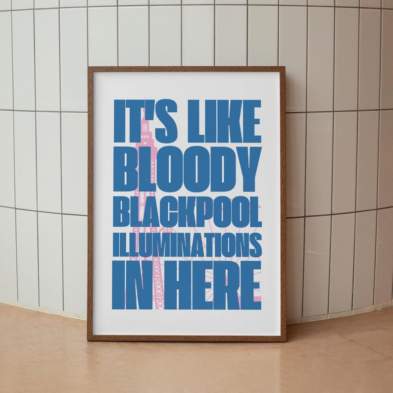 Pu&ograve; includere: Una stampa incorniciata con il testo "IT'S LIKE BLOODY BLACKPOOL ILLUMINATIONS IN HERE" in blu e rosa. La stampa &egrave; in una cornice di legno marrone. L'opera d'arte &egrave; esposta contro un muro piastrellato bianco e beige.