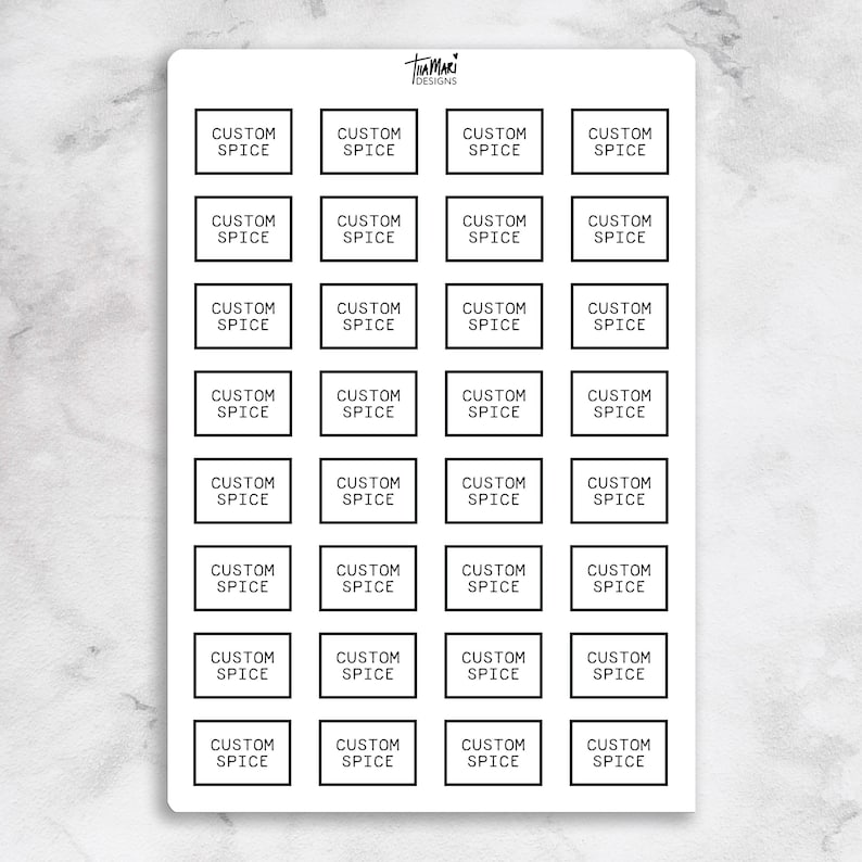May include: A sheet of custom spice labels with the text "CUSTOM SPICE" in a black font inside a black border. The labels are arranged in a grid pattern on a white background. The sheet has the "Tamari Designs" logo.