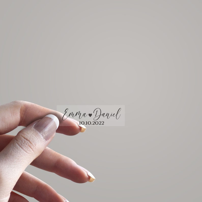 May include: A clear sticker with the text "Emma &hearts; Daniel 10.10.2022" in black cursive font.
