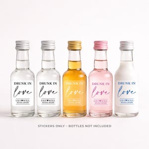 Puede incluir: Cinco botellas de vidrio pequeñas con tapas plateadas, doradas y rosas. Cada botella tiene una etiqueta que dice "DRUNK IN love" con un nombre y una fecha. Las botellas contienen líquidos transparentes, amarillos, rosas y blancos. El texto "STICKERS ONLY - BOTTLES NOT INCLUDED" está en la parte inferior.
