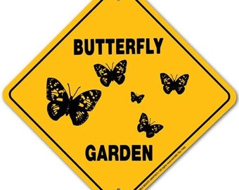 May include: Yellow diamond-shaped sign with black text that reads "Butterfly Garden". The sign features five black silhouettes of butterflies.