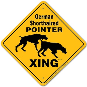 May include: Yellow diamond-shaped road sign with black text and silhouette images of two German Shorthaired Pointers. The sign reads "German Shorthaired Pointer Xing".