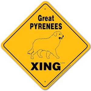 May include: Yellow diamond-shaped warning sign with black text and a black silhouette of a Great Pyrenees dog. The sign reads "Great Pyrenees Xing".