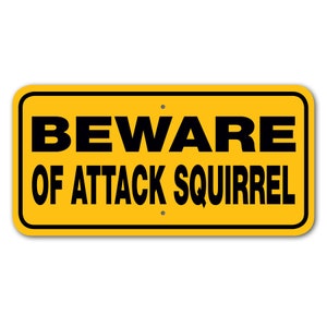 May include: Yellow metal sign with black text that reads "BEWARE OF ATTACK SQUIRREL".