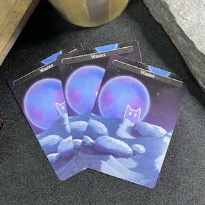 May include: Three trading cards featuring a purple planet with a white cat silhouette, set against a starry night sky. The word "Wastes" is printed at the top of each card. The cards have a blue and purple color scheme.
