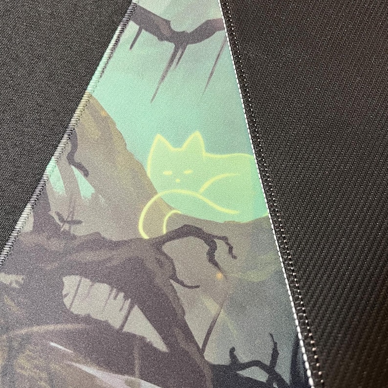 May include: A close-up of a dark green and black fabric with a glowing green cat silhouette on a branch. The fabric has a subtle texture and a white seam along the edge.