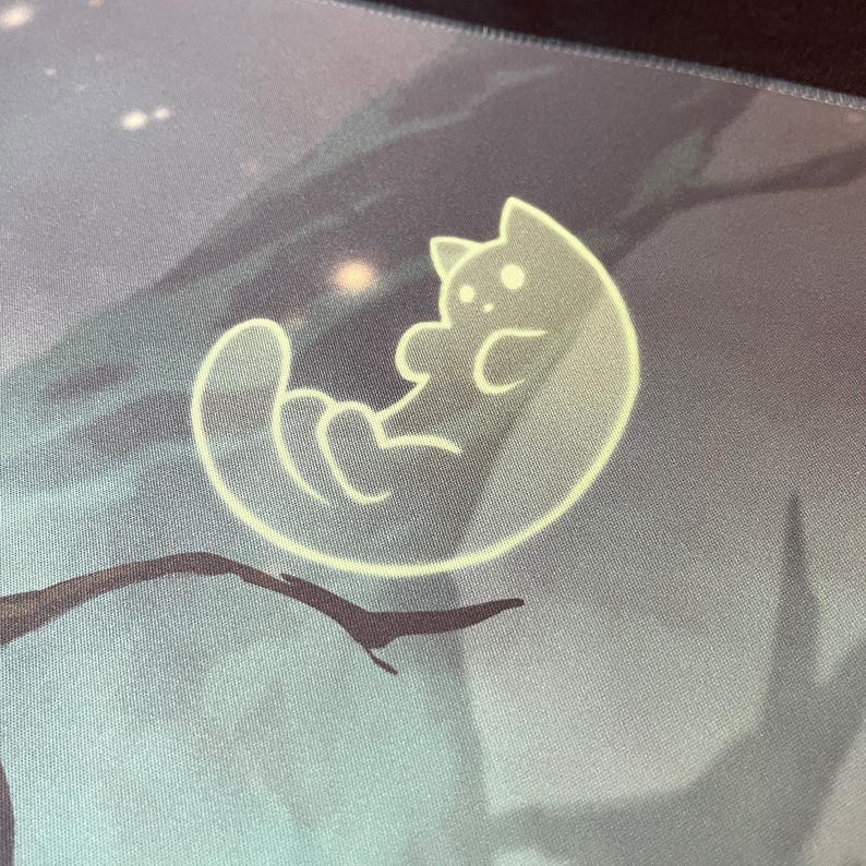 May include: A light gray mouse pad with a white outline of a cat curled up in a circle. The cat has two small, white circles for eyes.